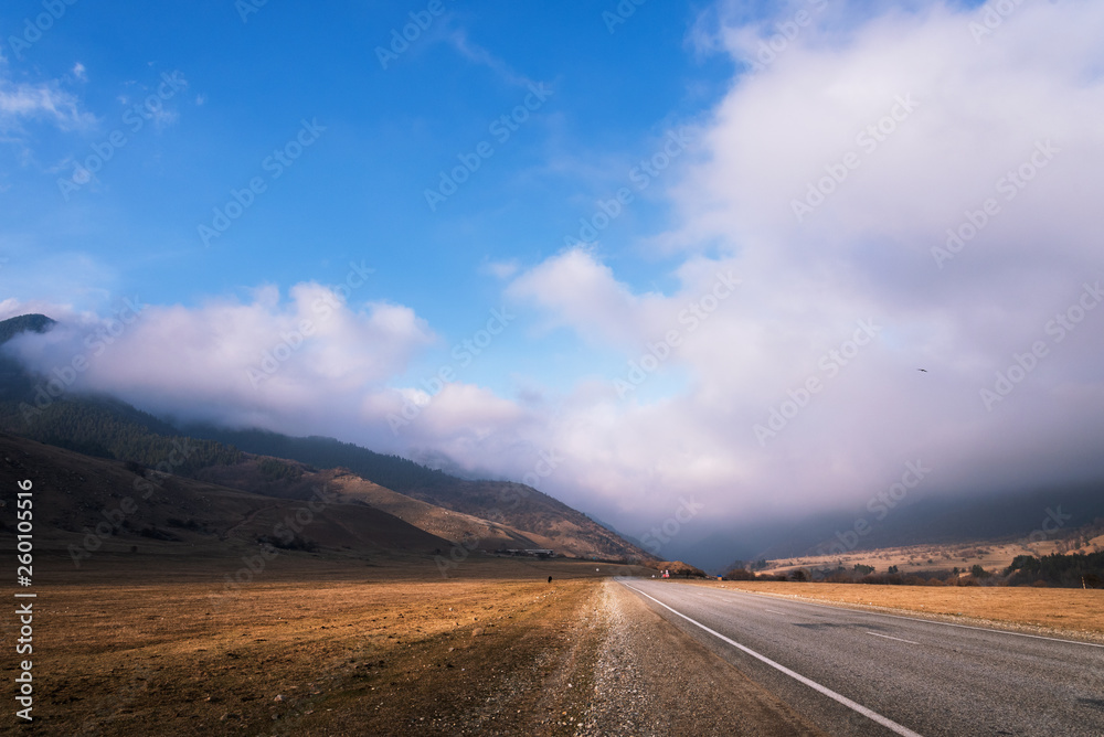 mountain road with low clouds and blue sky