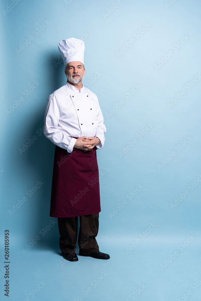 Full length of attractive smiling cheerful chef isolated on blue. Full length of attractive smiling cheerful chef isolated on blue.