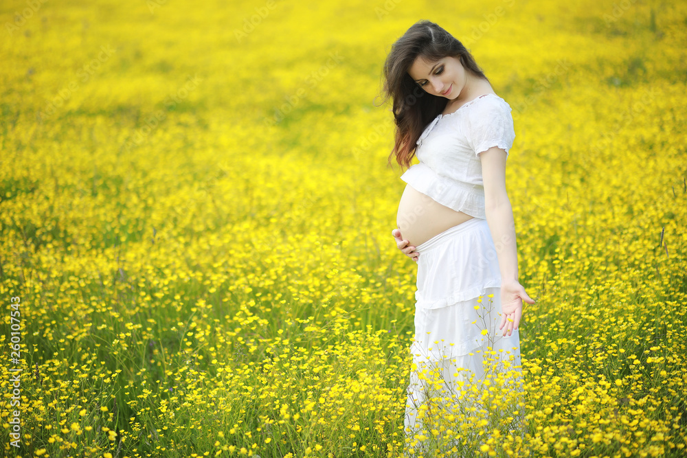 Pregnant woman in a dress in a field of flowers Pregnant woman in a dress in a field of flowers