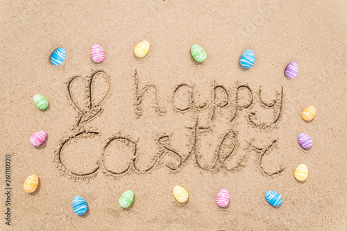 Happy easter lettering background with eggs on the sandy beach