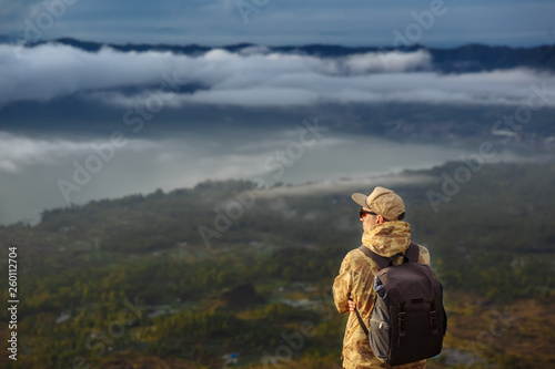 Man tourist looks at the sunrise on the volcano Batur on the island of Blai in Indonesia. Hiker man with backpack travel on top volcano, travel concept © Aliaksandr Barouski