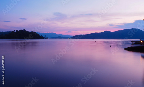 Beautiful violet sunset with reflexions in the motionless ocean - Island and hills in the background - panoramic 