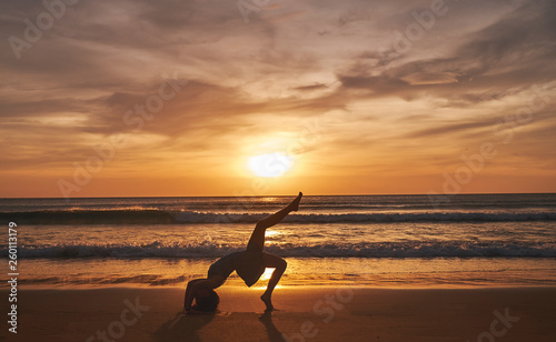 Obraz na plátně Girl on the beach during sunset doing yoga