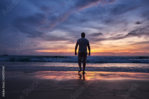 A man walks into the water at sunset