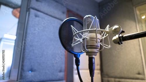 Studio microphone with shock mount and pop filter on professional tripod in acoustic foam room for best sound production on air and mix process in music industry and high quality broadcasting