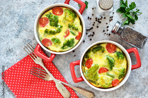 Casserole with broccoli and tomatoes on a concrete background. View from above.