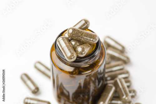 Medicine brown pills in the brown glass bottle on white background.