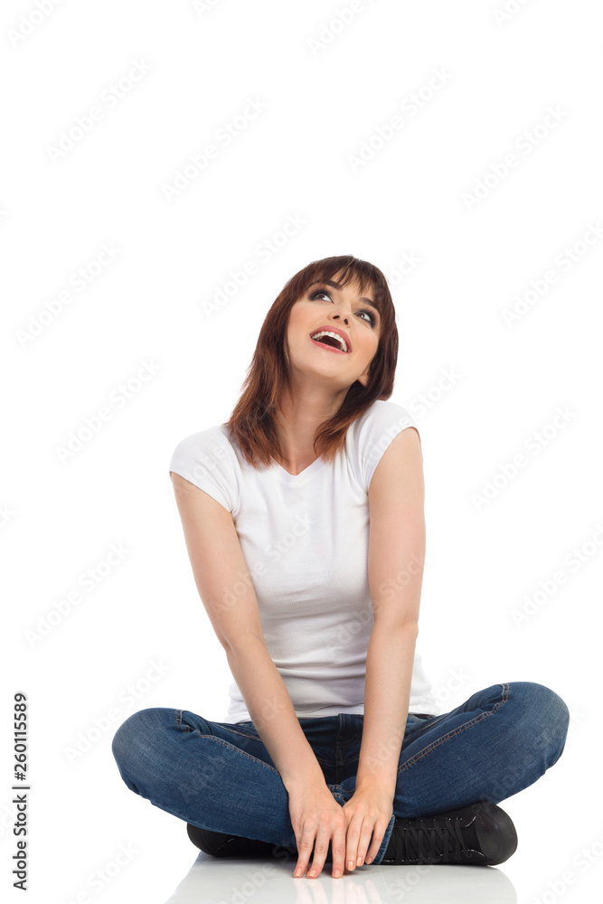 Young Woman Is Sitting Legs Crossed, Looking Up And Dreaming Young Woman Is Sitting Legs Crossed, Looking Up And Dreaming