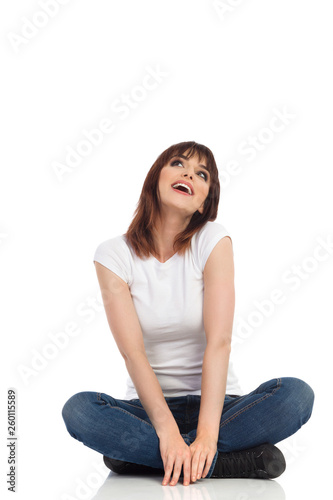 Young Woman Is Sitting Legs Crossed, Looking Up And Dreaming