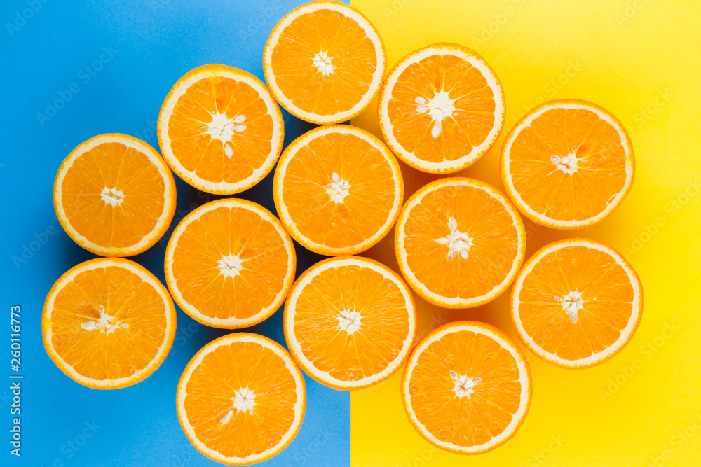 Cut halves of juicy orange on yellow blue background. Orange fruit, citrus minimal concept. Creative summer food minimalistic background. Top view, copy space Cut halves of juicy orange on yellow blue background. Orange fruit, citrus minimal concept. Creative summer food minimalistic background. Top view, copy space