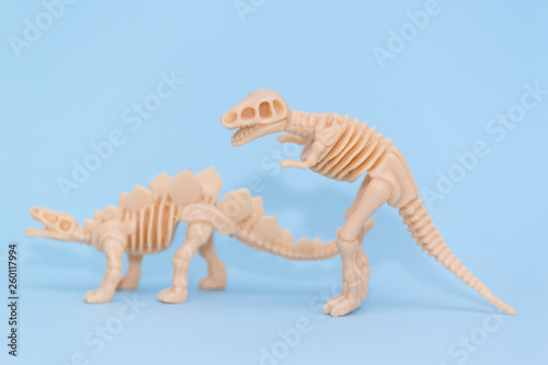 Plastic toy animal dinosaur skeleton on blue background. © vittaliya