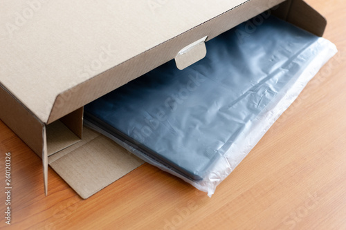 unpacking new blue laptop at wooden desk. cellophane packaging. post and delivery concept.