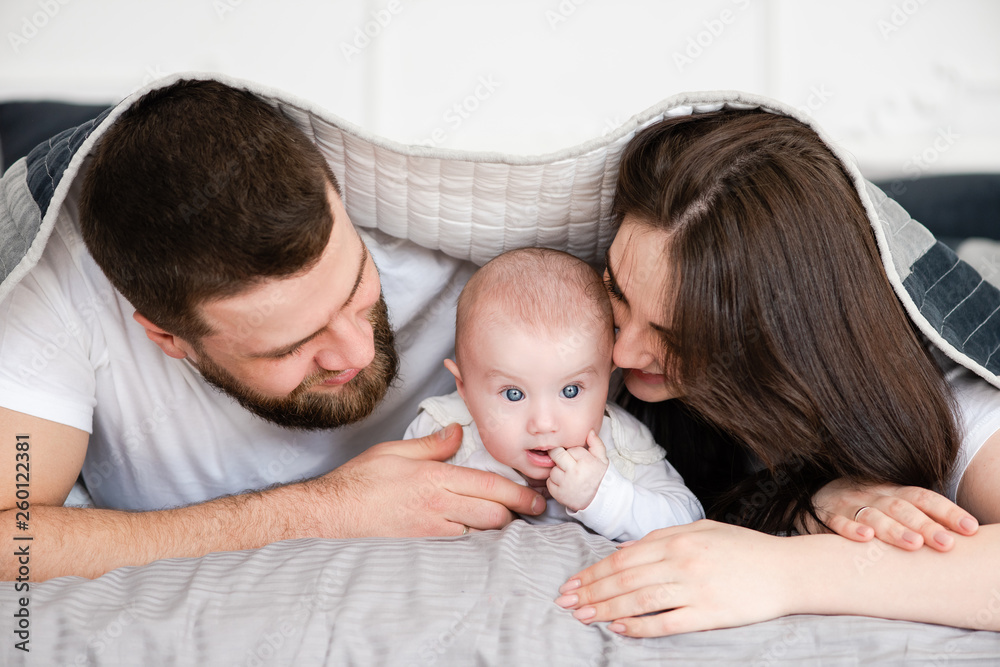 Young smiling family with daughter under blanket