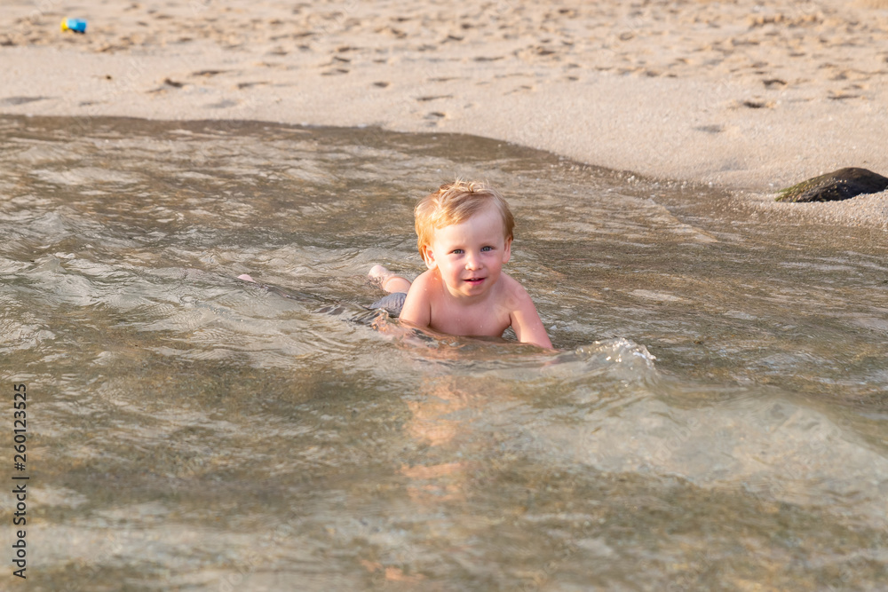 Little boy lying on the beach in the water Little boy lying on the beach in the water