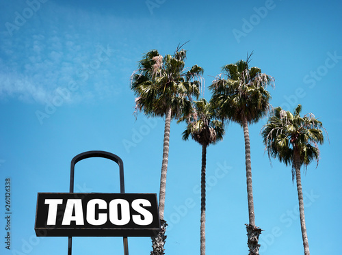 aged and worn tacos sign with palm trees