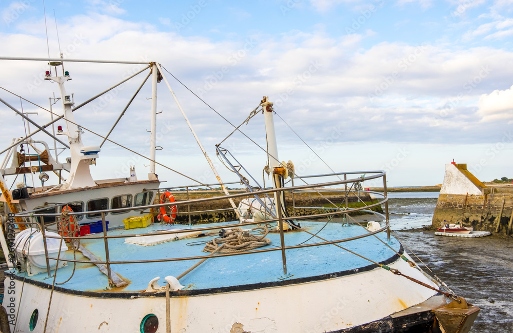 A fishing boat in the port of Saint-Vaast-la-Hougue at low tide . Normandy, France