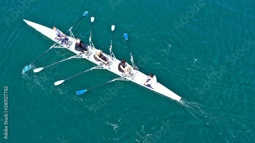 Aerial drone bird's eye view of sport canoe operated by team of young men and women in open ocean sea