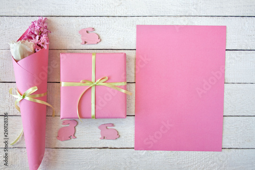  Różowo-białe tło z pudełkiem przewiązanym wstążką, kwiatami i zajączkami