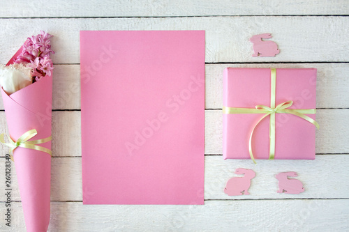  Różowo-białe tło z pudełkiem przewiązanym wstążką, kwiatami i zajączkami