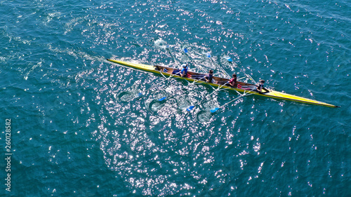 Aerial drone bird's eye view photo of yellow sport canoe operated by team of young team in emerald clear sea