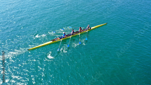 Aerial drone bird s eye view photo of yellow sport canoe operated by team of young team in emerald clear sea