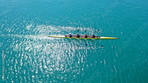 Aerial drone bird's eye view photo of yellow sport canoe operated by team of young team in emerald clear sea © aerial-drone