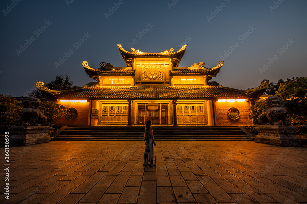 A woman poses in front of a Buddhist temple in Vietnam. Bai Dinh Pagoda