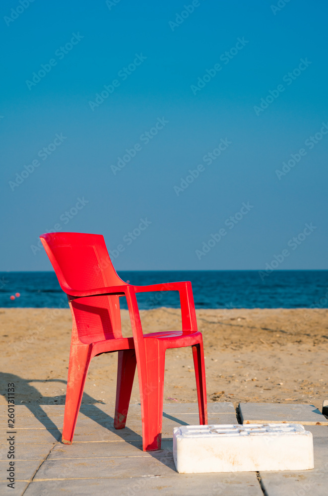 red plastic chair on beach of Lido di Spina, Italy