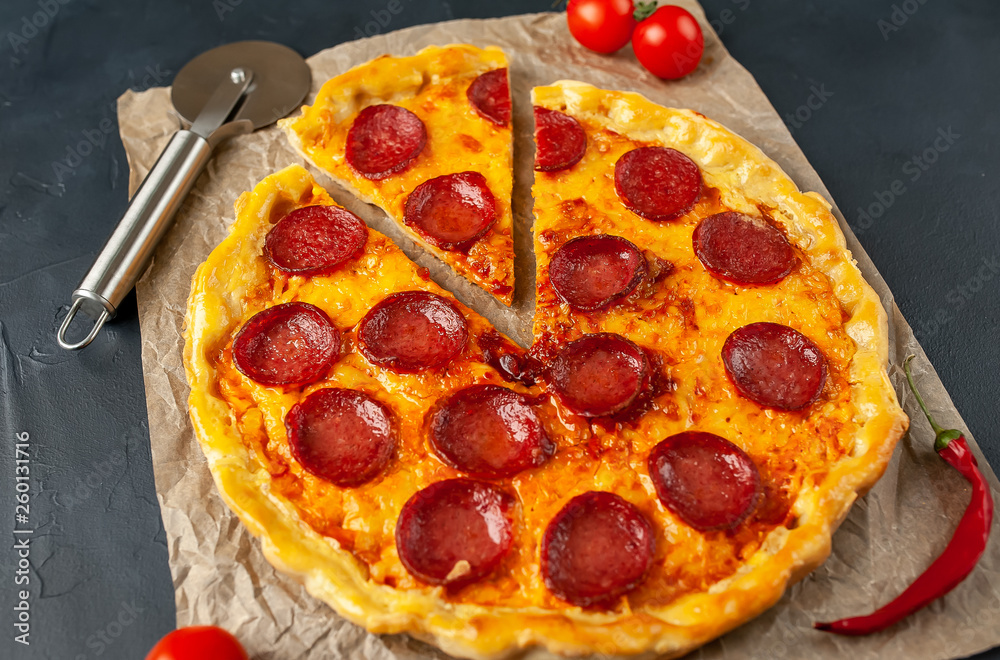 Tasty pepperoni pizza of tomatoes and ingredients on concrete background. Tasty pepperoni pizza of tomatoes and ingredients on concrete background.