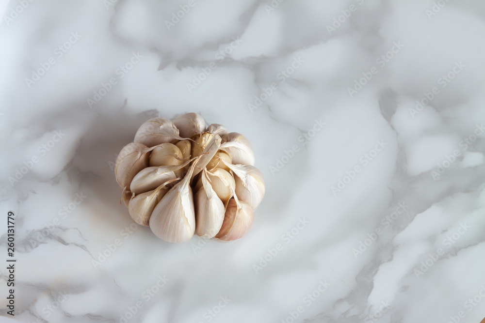 Close-up one fresh organic non-standard garlic on marble board background. Close-up one fresh organic non-standard garlic on marble board background.