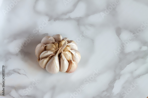 Close-up one fresh organic non-standard garlic on marble board background.