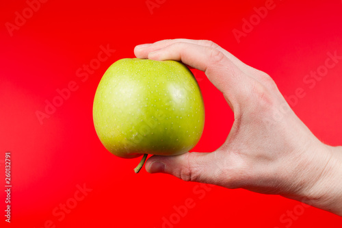 Hand holding tasty organic green delicious apple Isolated on red Background