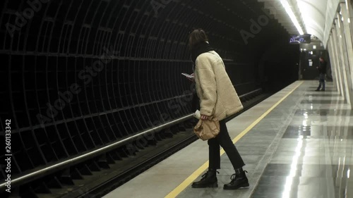  woman is waiting for a train in the subway