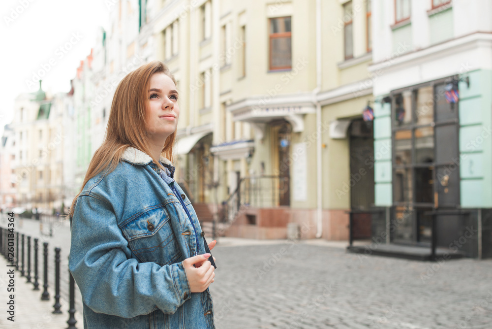 Beautiful girl in a jeans jacket and the streets of the old European town. Portrait of a teenage girl against the background of the old town.