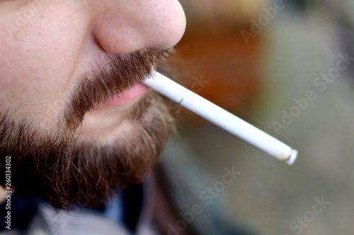 Portrait of brutal adult working  man after labor day  with a beard close up smoking  cigarette, unheatlhy living photo