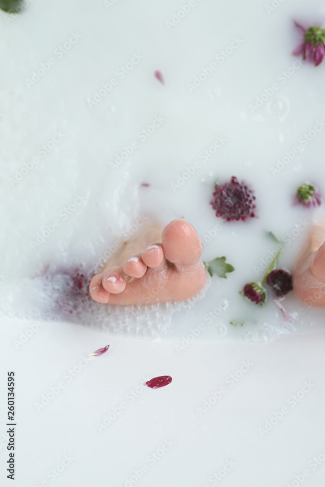 Fototapeta premium foot in the water with flowers, milk; feet close up, feet in the bathroom