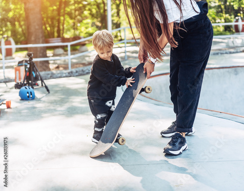 little boy carries a big skateboard outside