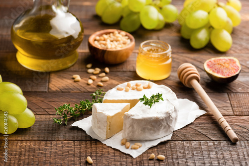 Camembert or Brie Cheese on Wooden Table Served With Grapes, Figs, Nuts And Honey