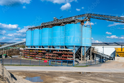 Big blue metallic Industrial silos for the production of cement at an industrial cement plant on the background of blue sky.