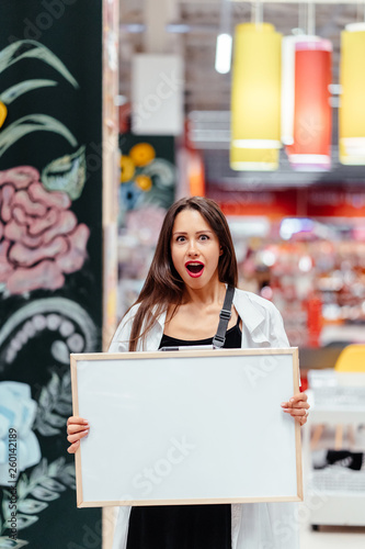 Smiling brunette woman holding white blank board