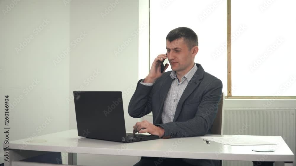 Adult businessman talking on phone in office Adult businessman talking on phone in office