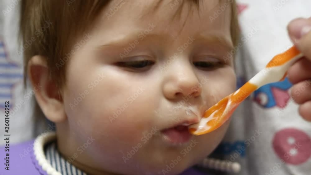 A Toddler Eats With A Spoon.