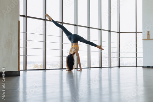 young attractive girl doing fitness exercises with yoga on the floor against the background of panoramic windows