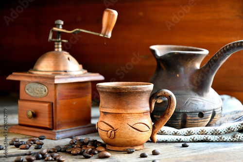 Manual coffee grinder, a Turk on a napkin and a cup of coffee, on a wooden background.