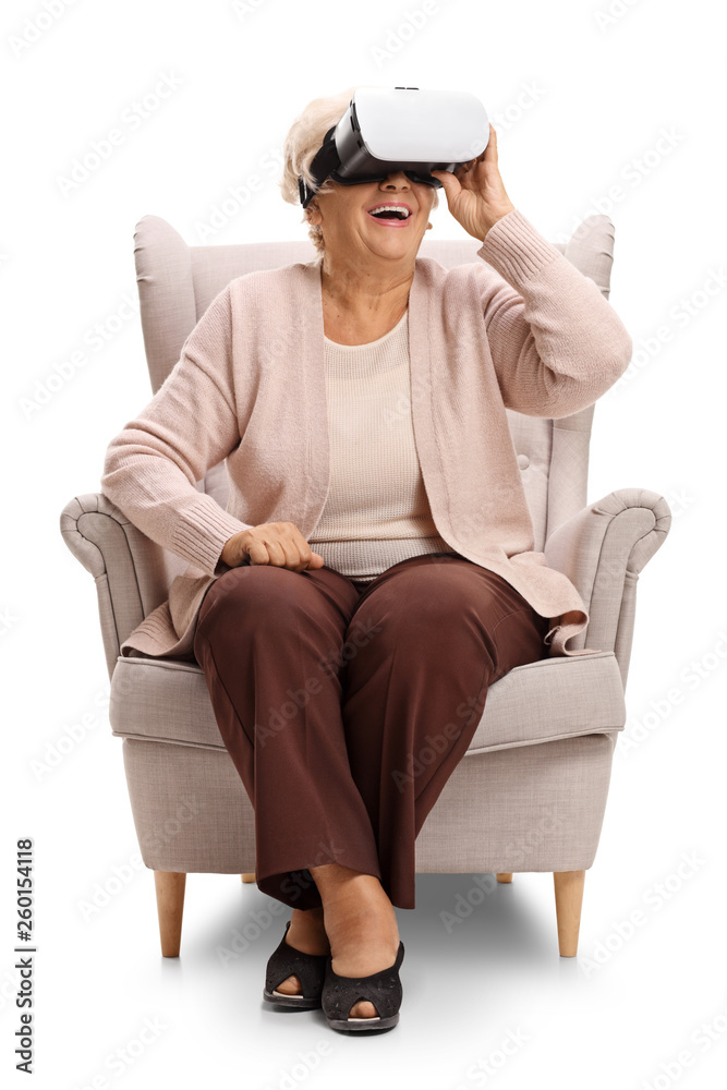 Excited elderly woman sitting in an armchair and using a VR headseat