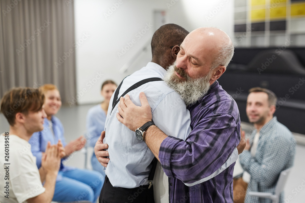 Side view portrait of senior man hugging psychologist during therapy session in support group, copy space Side view portrait of senior man hugging psychologist during therapy session in support group, copy space