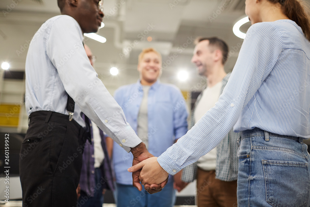 Low angle view at of people holding hands standing in circle during therapy session in support group, copy space Low angle view at of people holding hands standing in circle during therapy session in support group, copy space