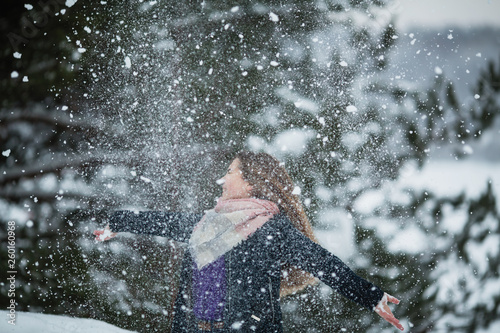 Funny girl playing with snow in amazing park at winter.