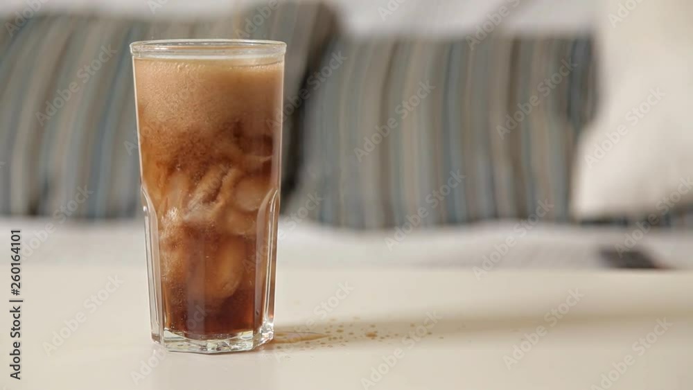 A girl sits on a couch and pours a cola into a glass A girl sits on a couch and pours a cola into a glass