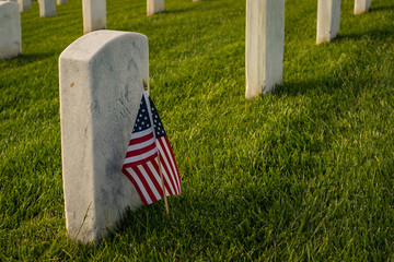 American flag by a grave marker of a soldier. Can be used for Memorial Day or Independence Day, grief counseling, loss, sadness, sacrifice